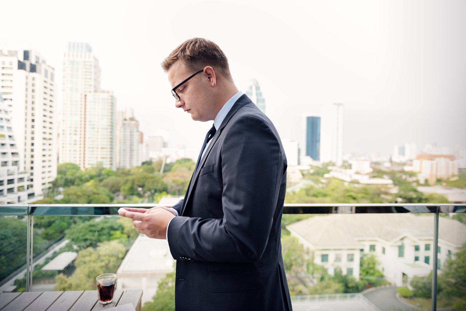 Overseas investor at a laptop with an off-plan brochure and a bank transfer screen, Dubai skyline behind — is it safe to buy property in Dubai as a foreigner?